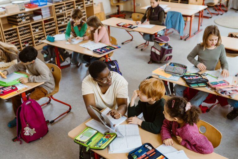 Teacher,Explaining,Male,And,Female,Students,Sitting,In,Classroom